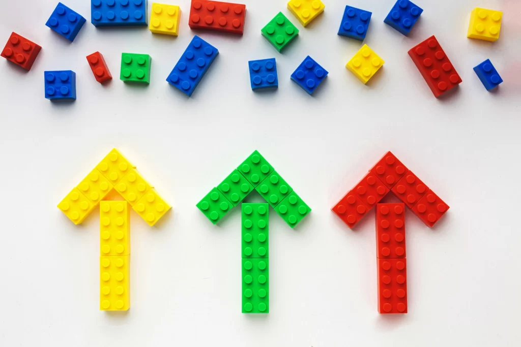 Image avec des légos 3 flêches de couleurs différentes jaune verte, rouge en légo qui montre les légos dispersés en haut de l'image.