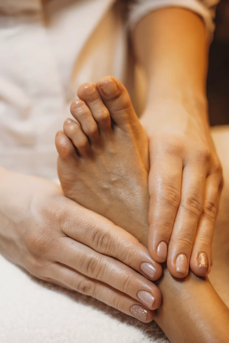 Photo en gros plan d'un pied massé avec deux mains.